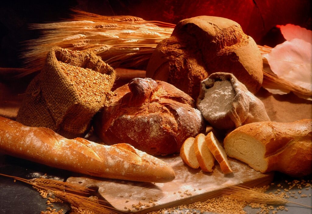 an assortment of different kinds of bread, wheat, and bags of grain