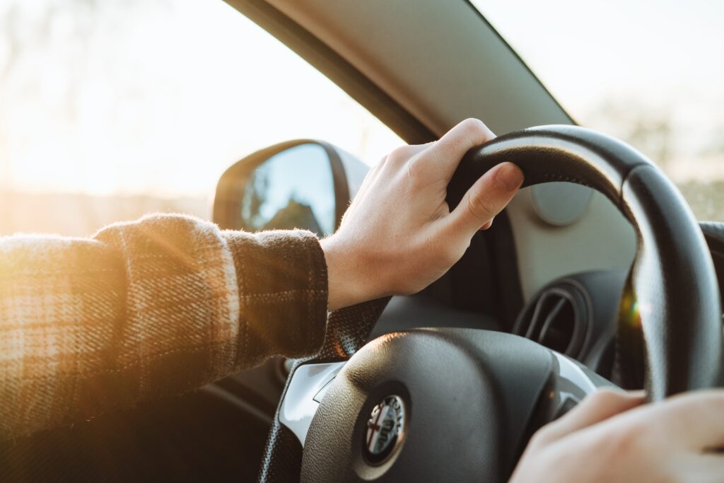 hands in a plaid jacket holding the steering wheel of a car