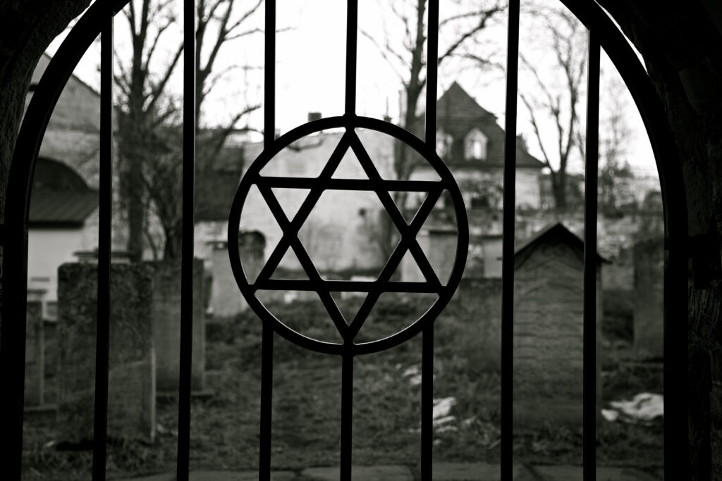 black and white photo of gate of a jewish cemetery with jewish star