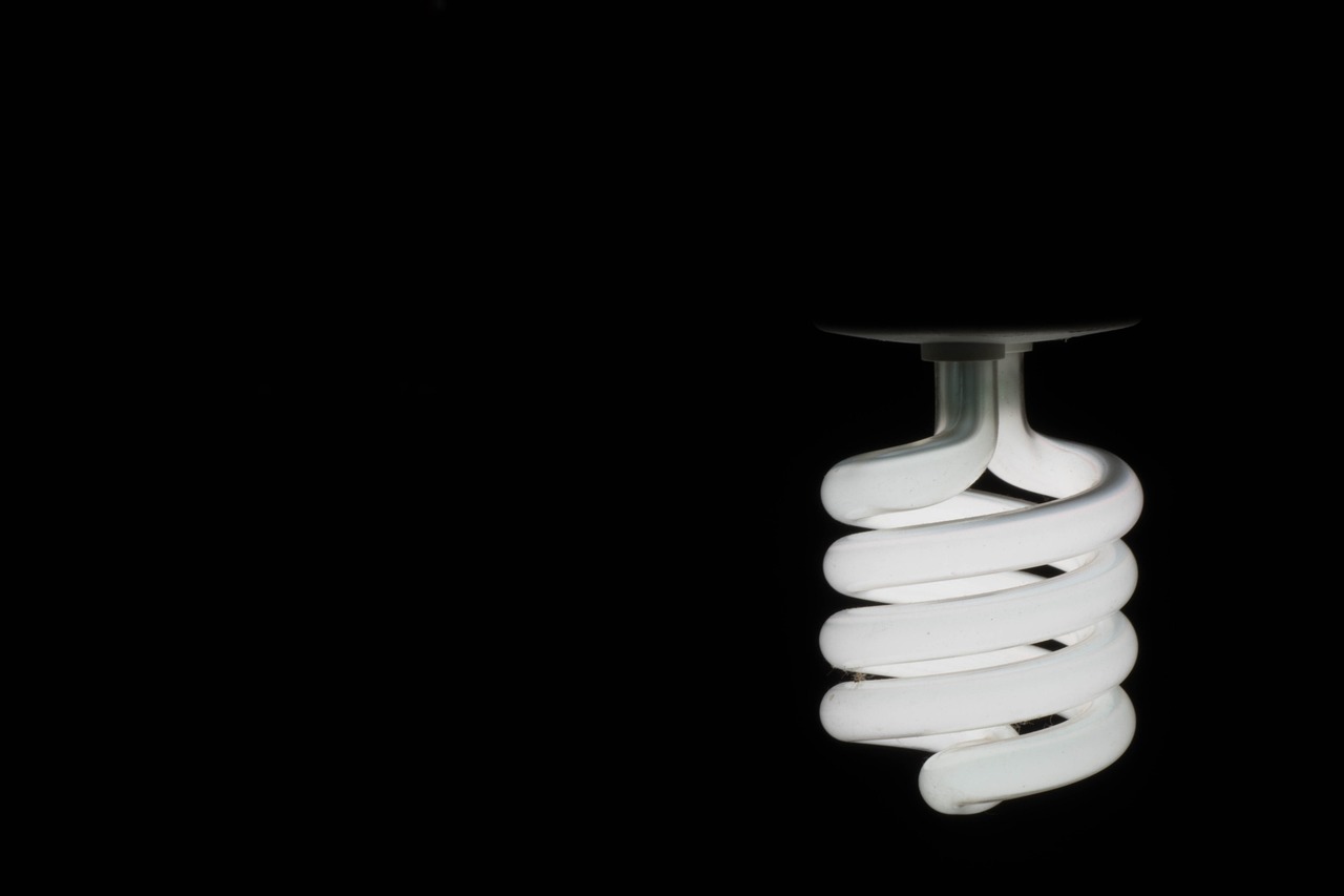 Close-up of a glowing spiral light bulb against a dark background