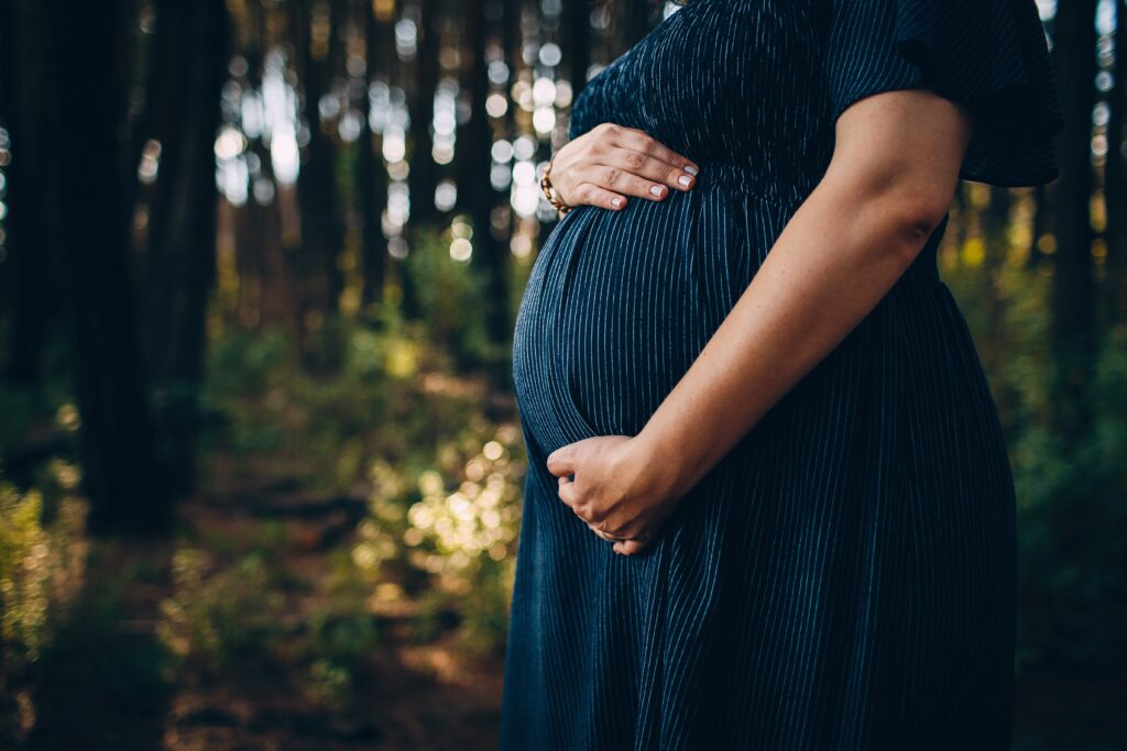 pregnant woman in blue dress holding belly