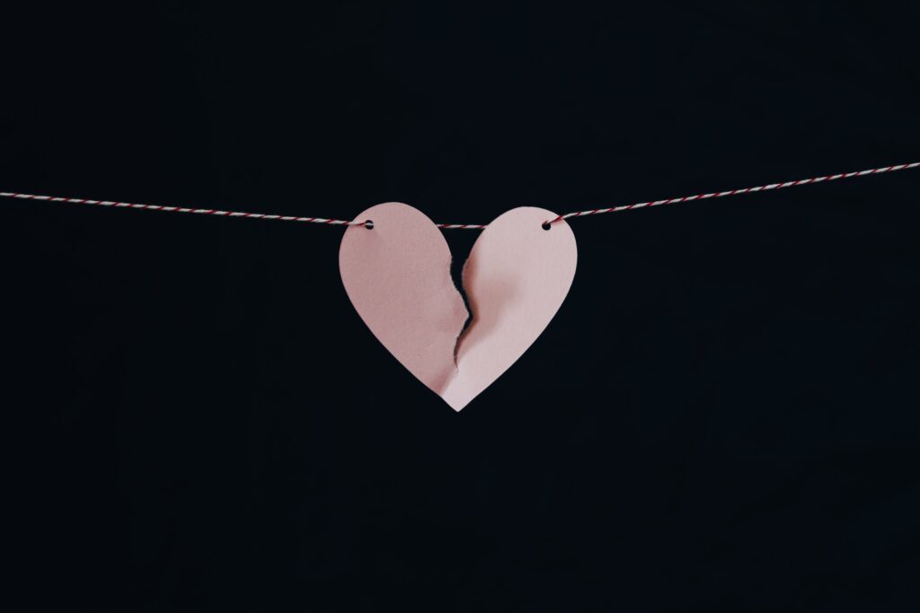 torn pink paper heart on a string