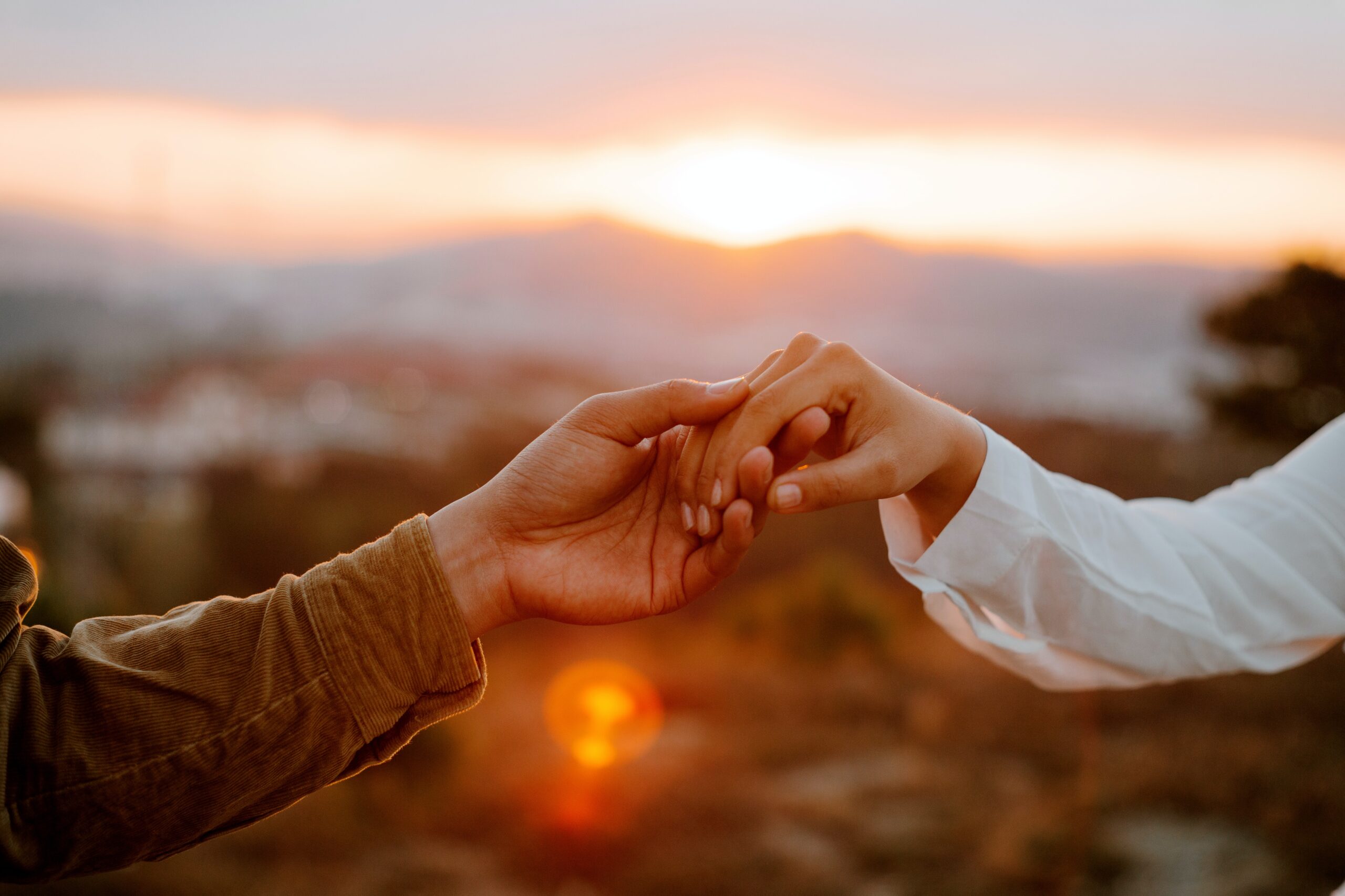 two people holding hands at sunset