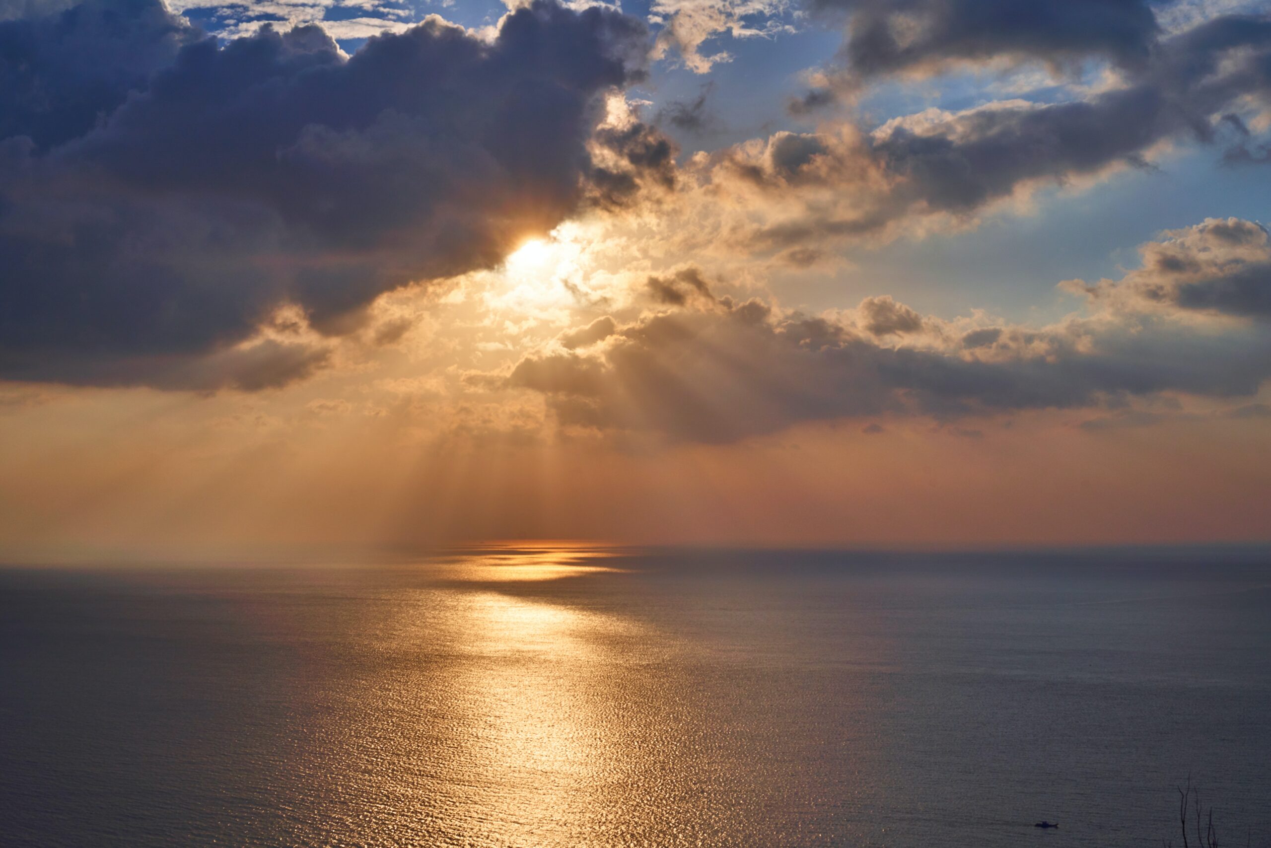 cloudy sky with sunbeams over water