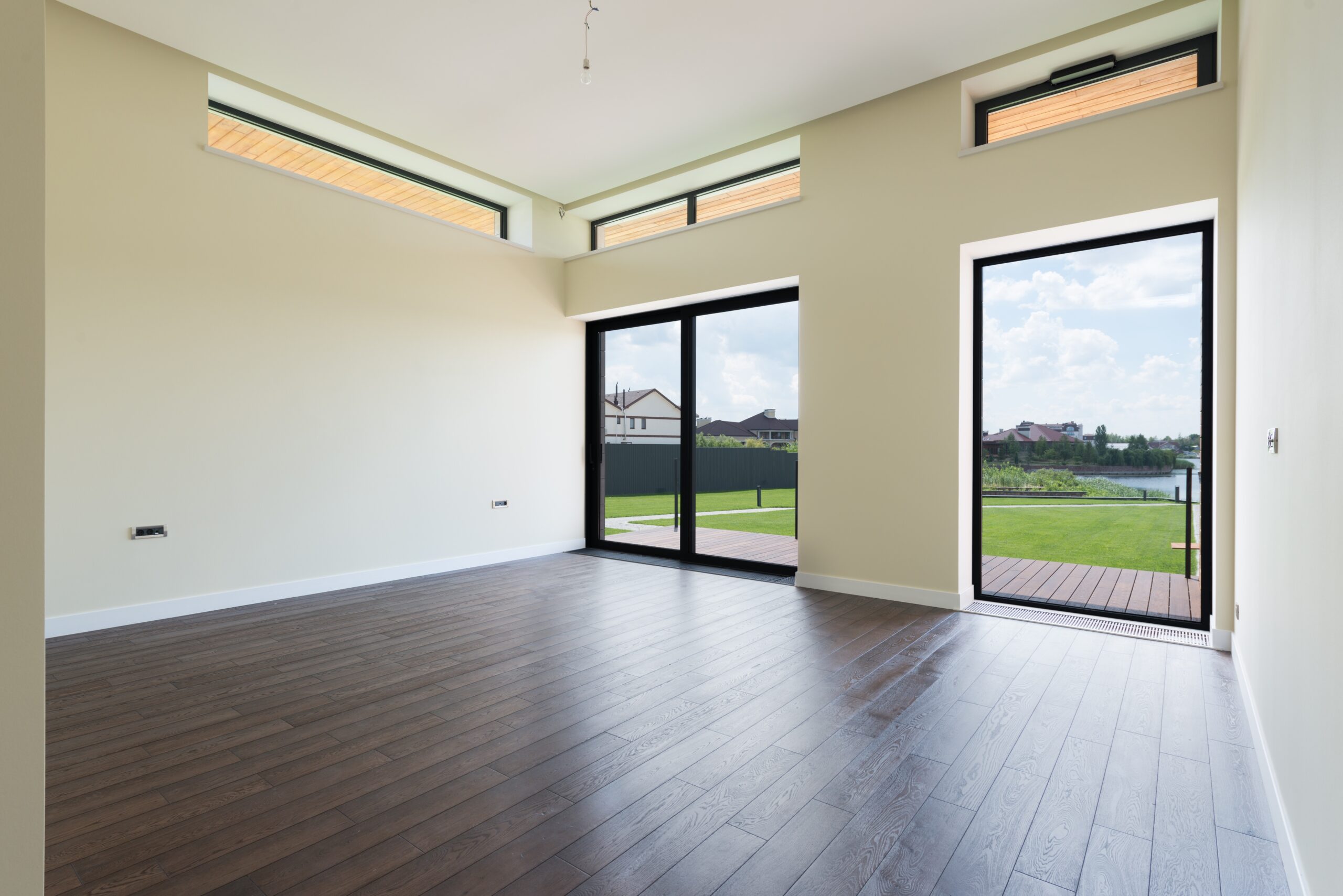 empty room with sliding glass doors to green lawn and lake