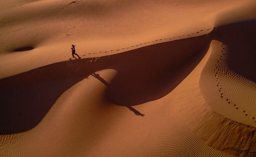 person walking in desert sand dunes