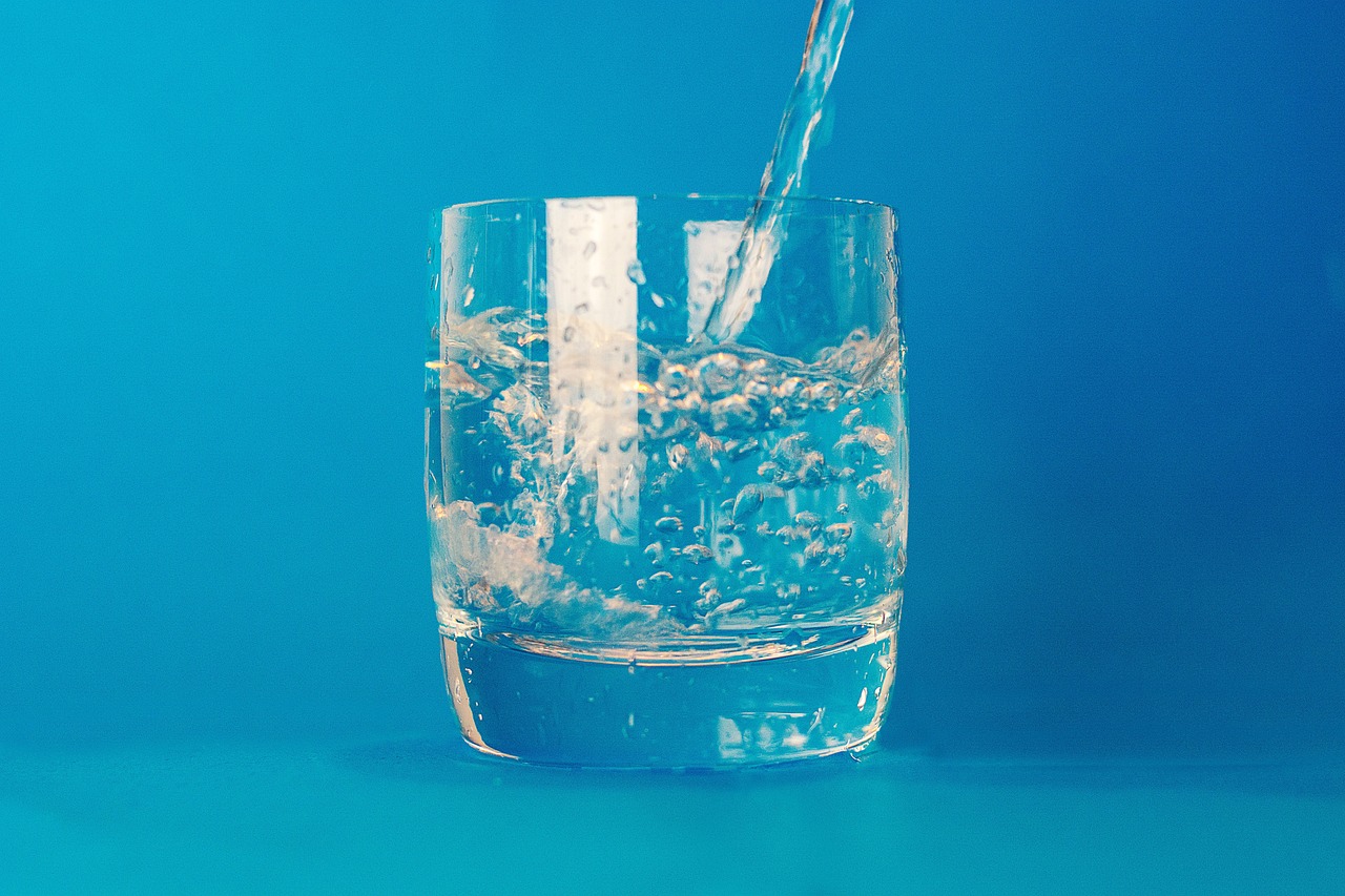 a stream of water is pouring into a short round glass