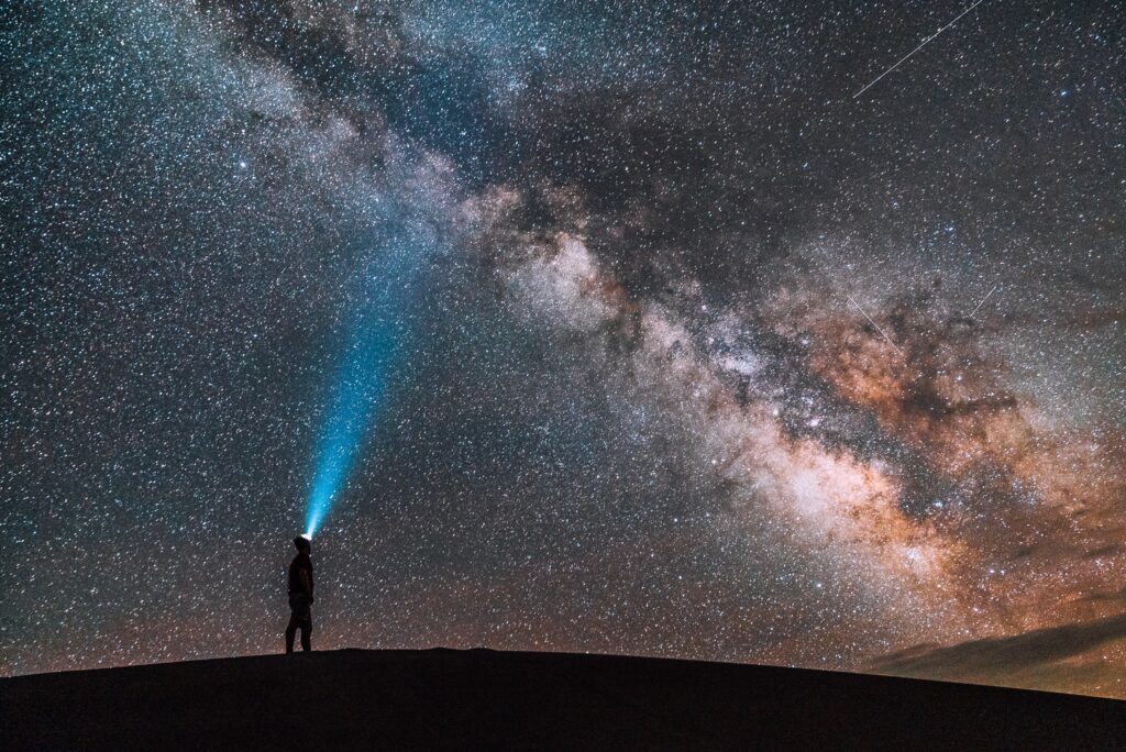 person shining light onto starry sky