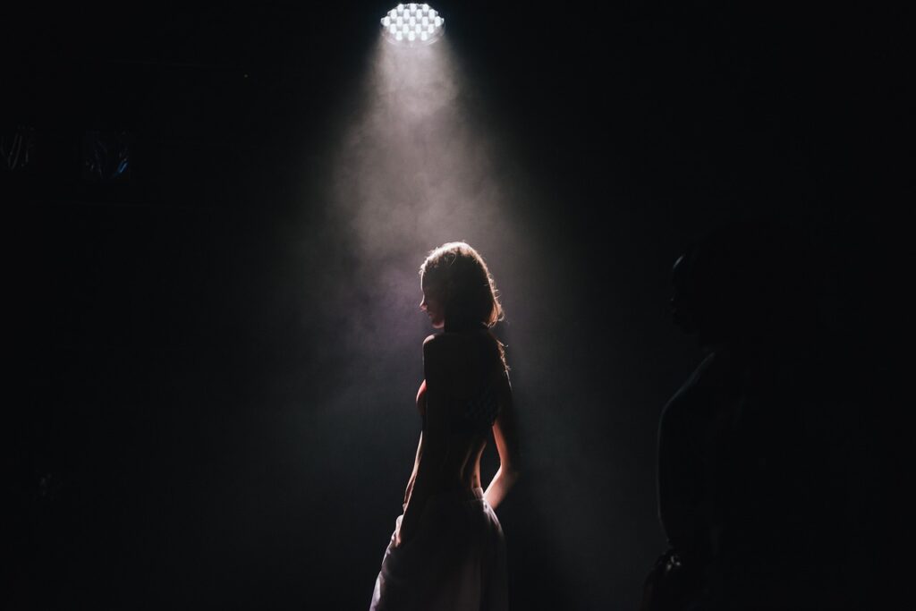 silhouette of a person standing under a spotlight in the dark