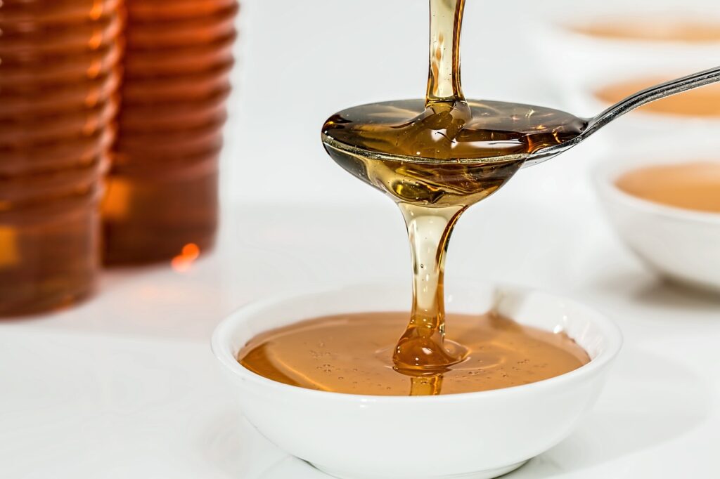 honey dripping onto a spoon and overflowing into a small bowl