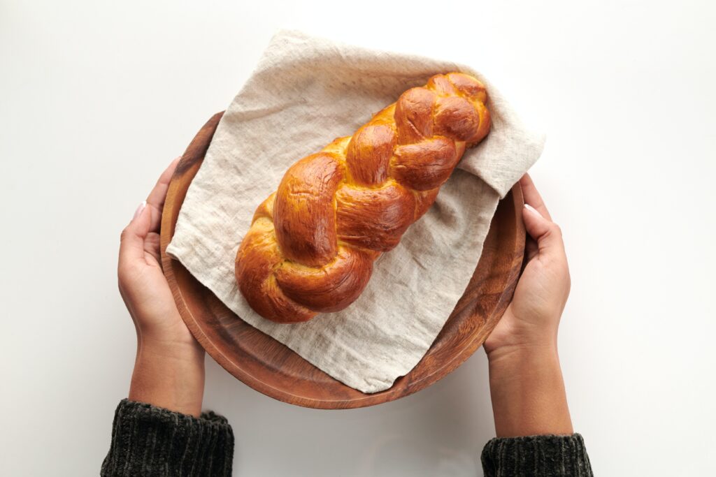 hands holding round platter with challah