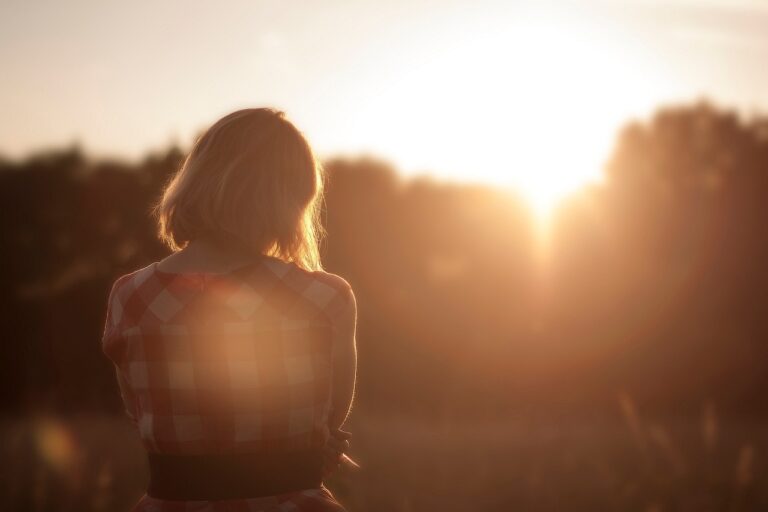 the back of a person looking down as the sun sets