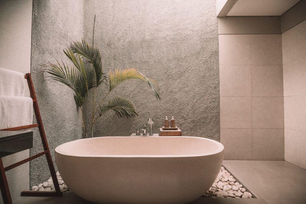 upscale bathroom with large ceramic tub and fern