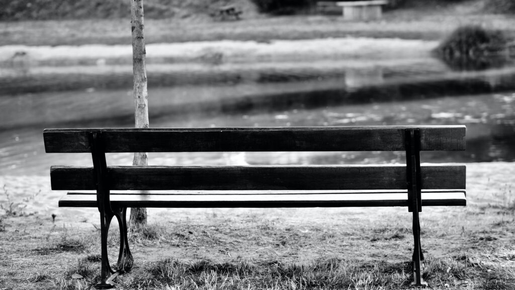black and white photo of empty park bench