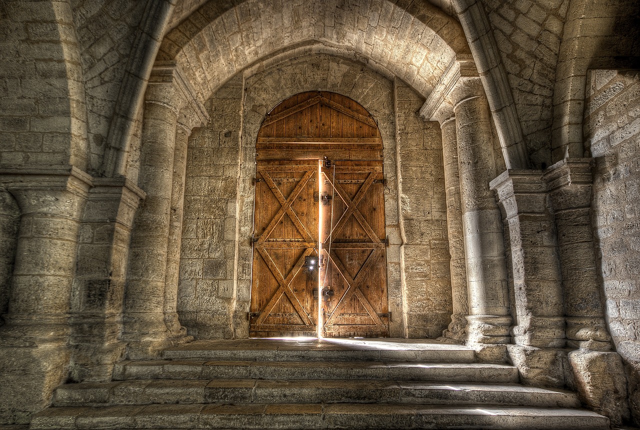 two large wooden doors, one is slighty ajar with light coming through