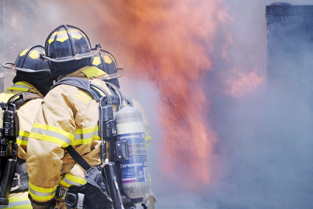 the back of a firefighter with blurred fire in the background