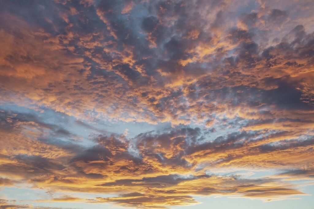 dark pink and golden clouds cover a light blue sky