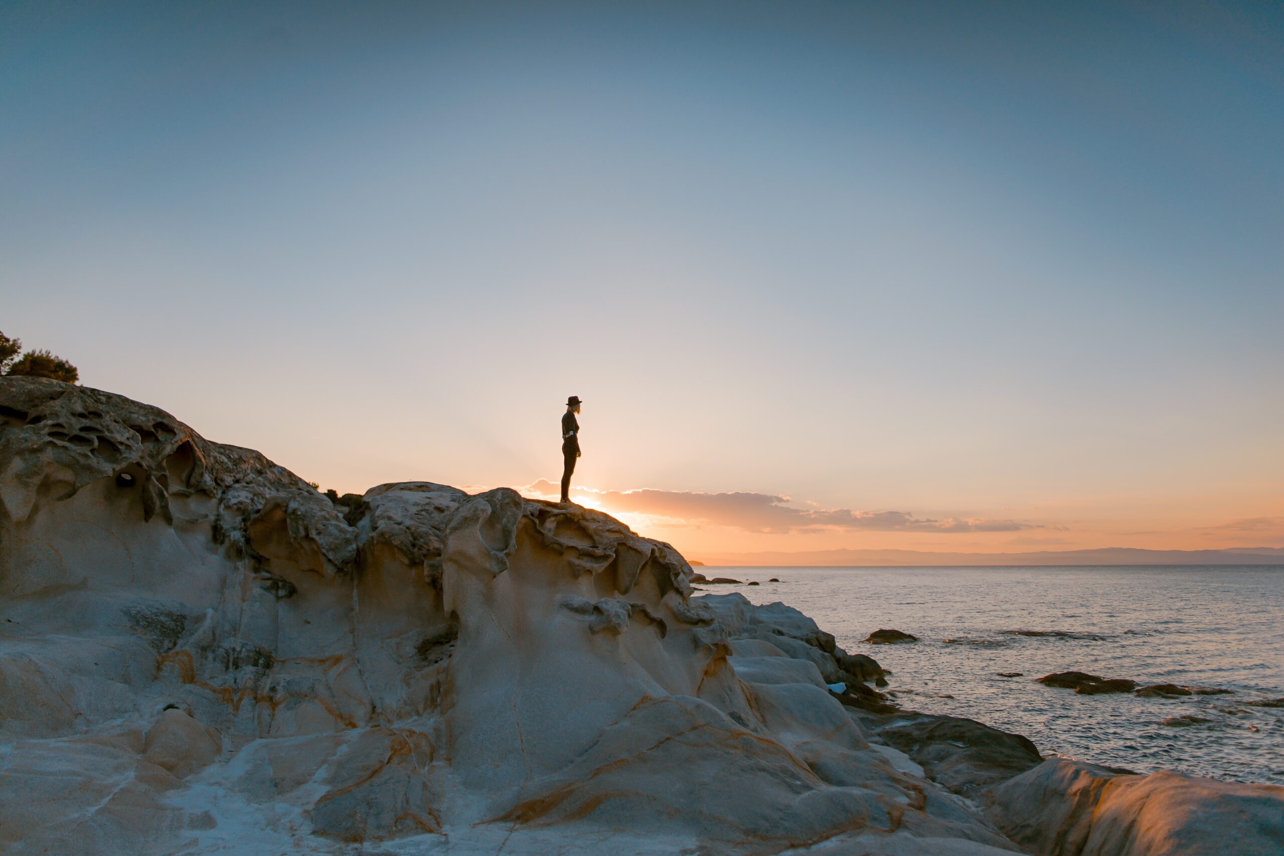 silhouetted woman standing on sand dune