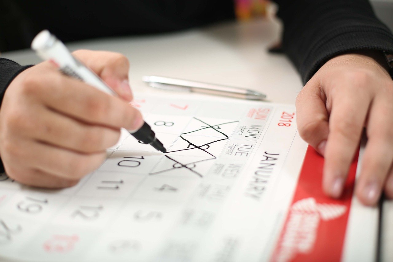 a person is crossing off days on a paper calendar