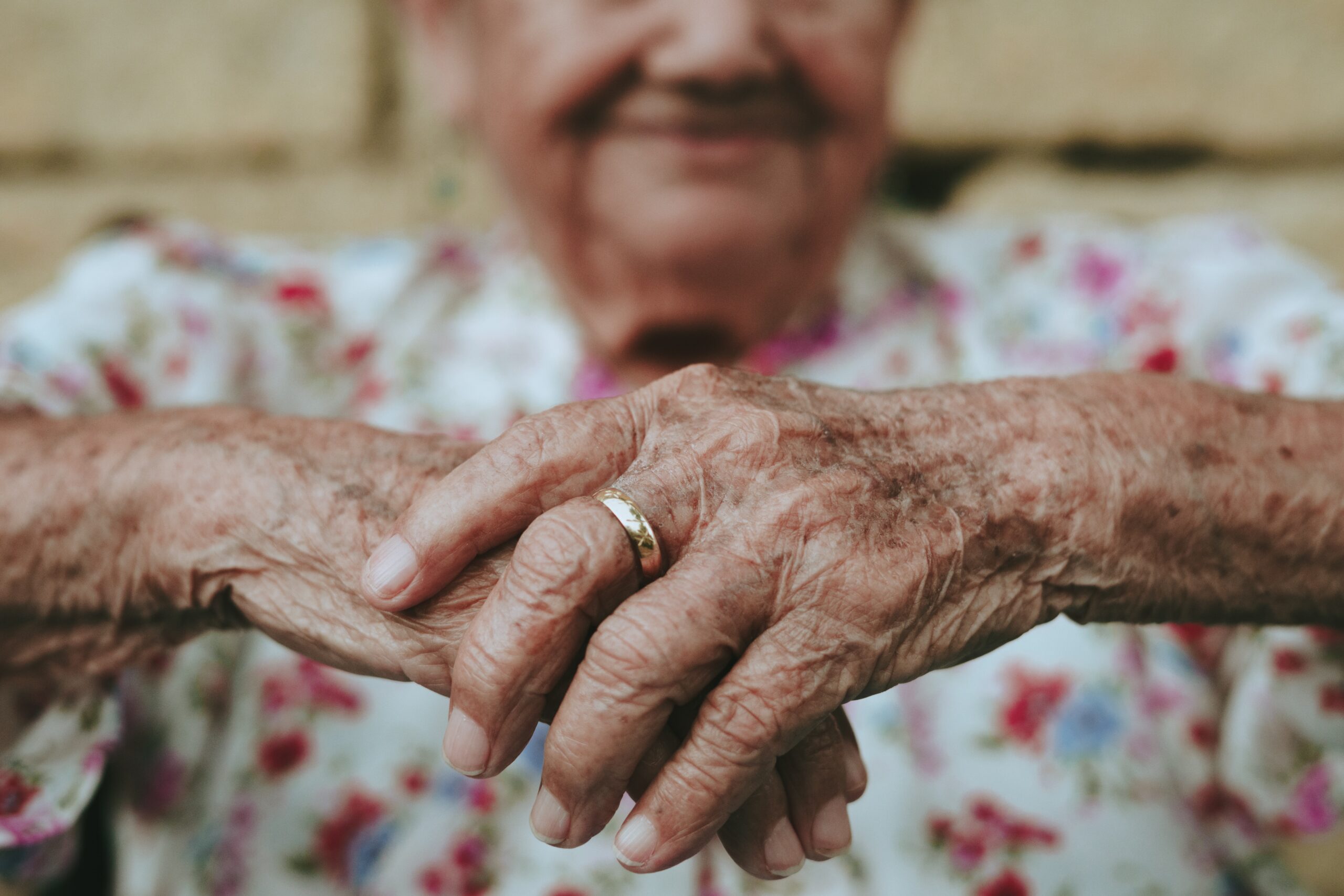 wrinkled hands with wedding ring on one finger