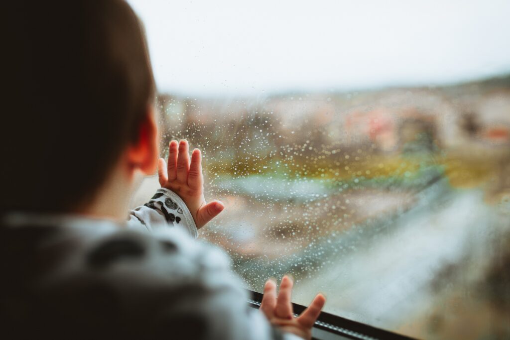 child hands on rainy window