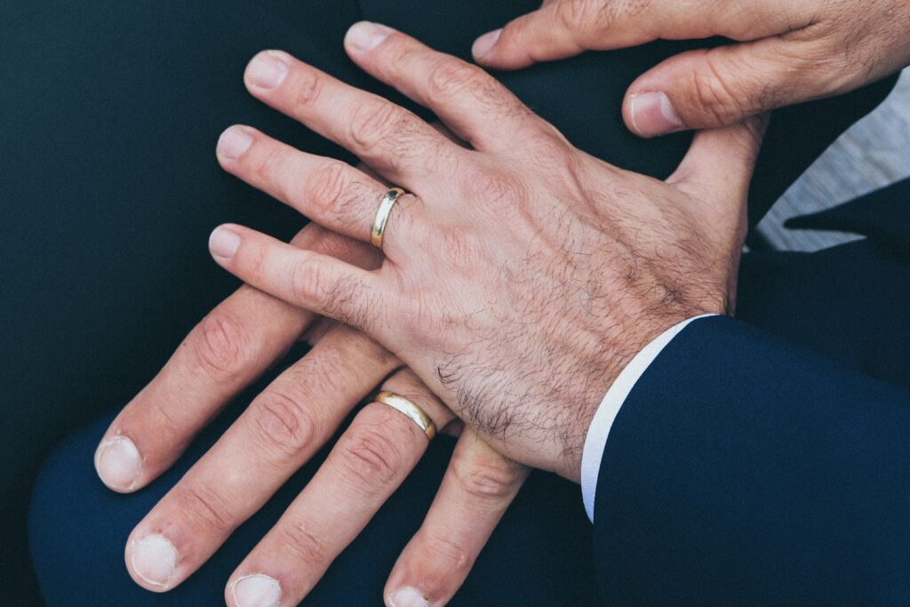 two mens hands with wedding rings
