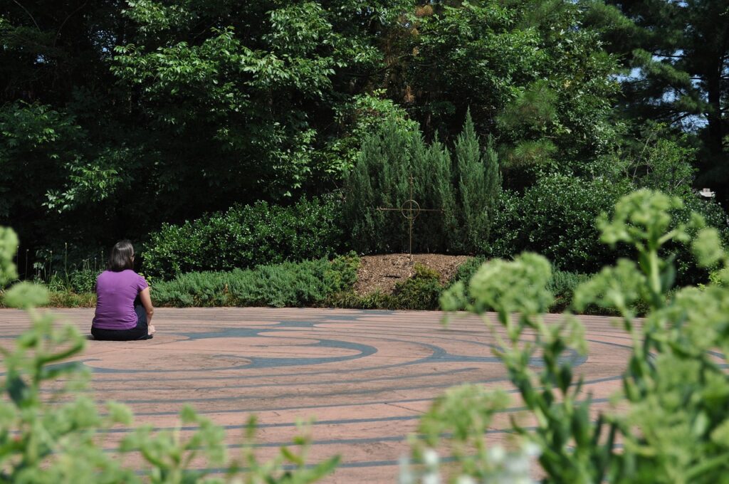 a person is seated in the middle of a labyrinth surrounded by trees