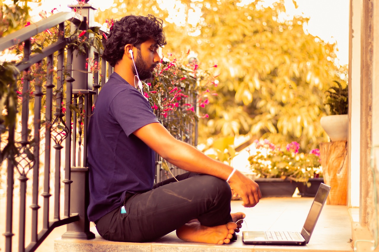 a person sits cross-legged side profile, eyes closed, with earbuds in