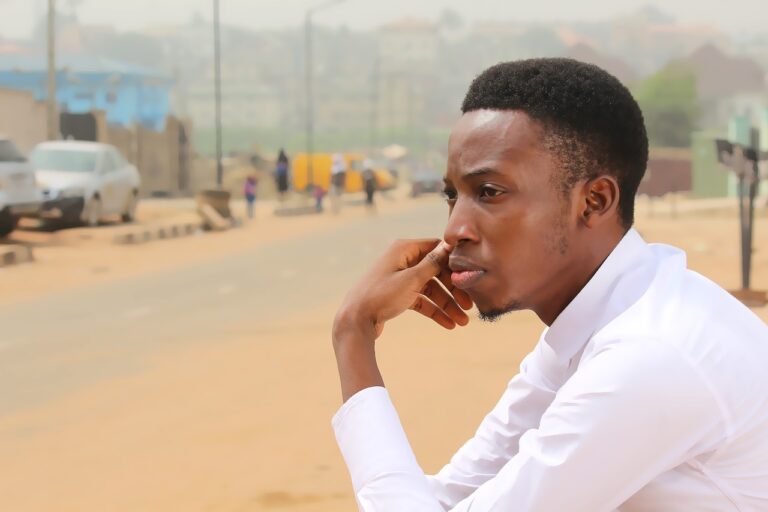 a person sits looking out on a dirt road