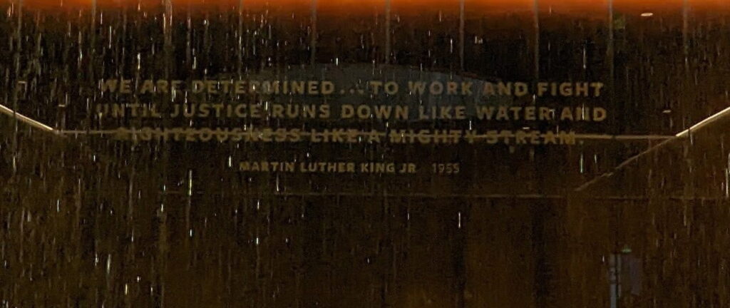 A wall with a water feature and a Martin Luther King Jr. quote about justice, partly obscured by falling water.