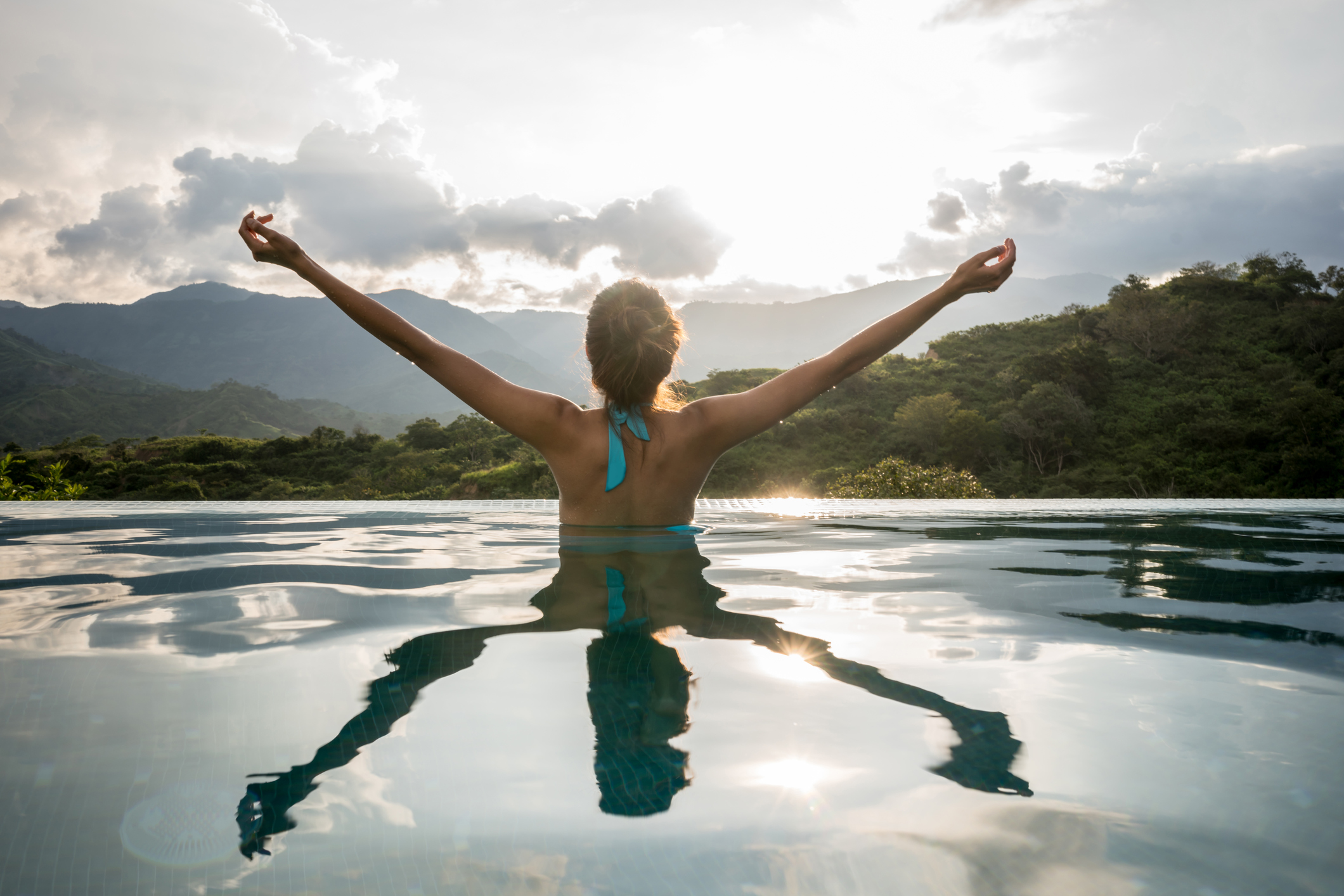 a person stands in water with their arms raised toward the sky