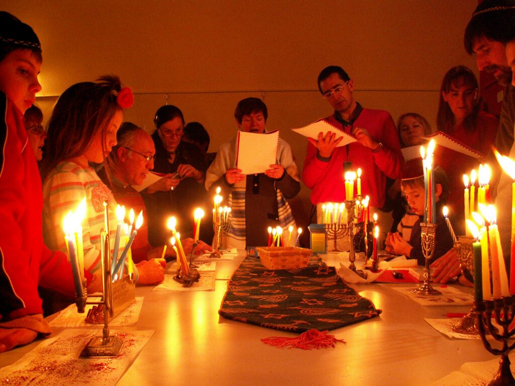 people gather to light multiple hanukkah menorahs