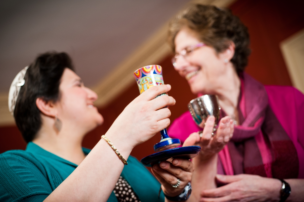 Two people smiling and clinking colorful cups in a celebratory gesture.