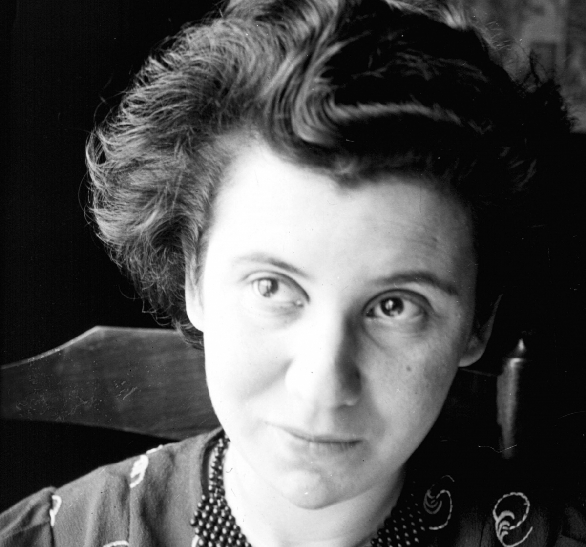 Black and white portrait of a person with short hair, wearing a patterned top, gazing slightly upward.