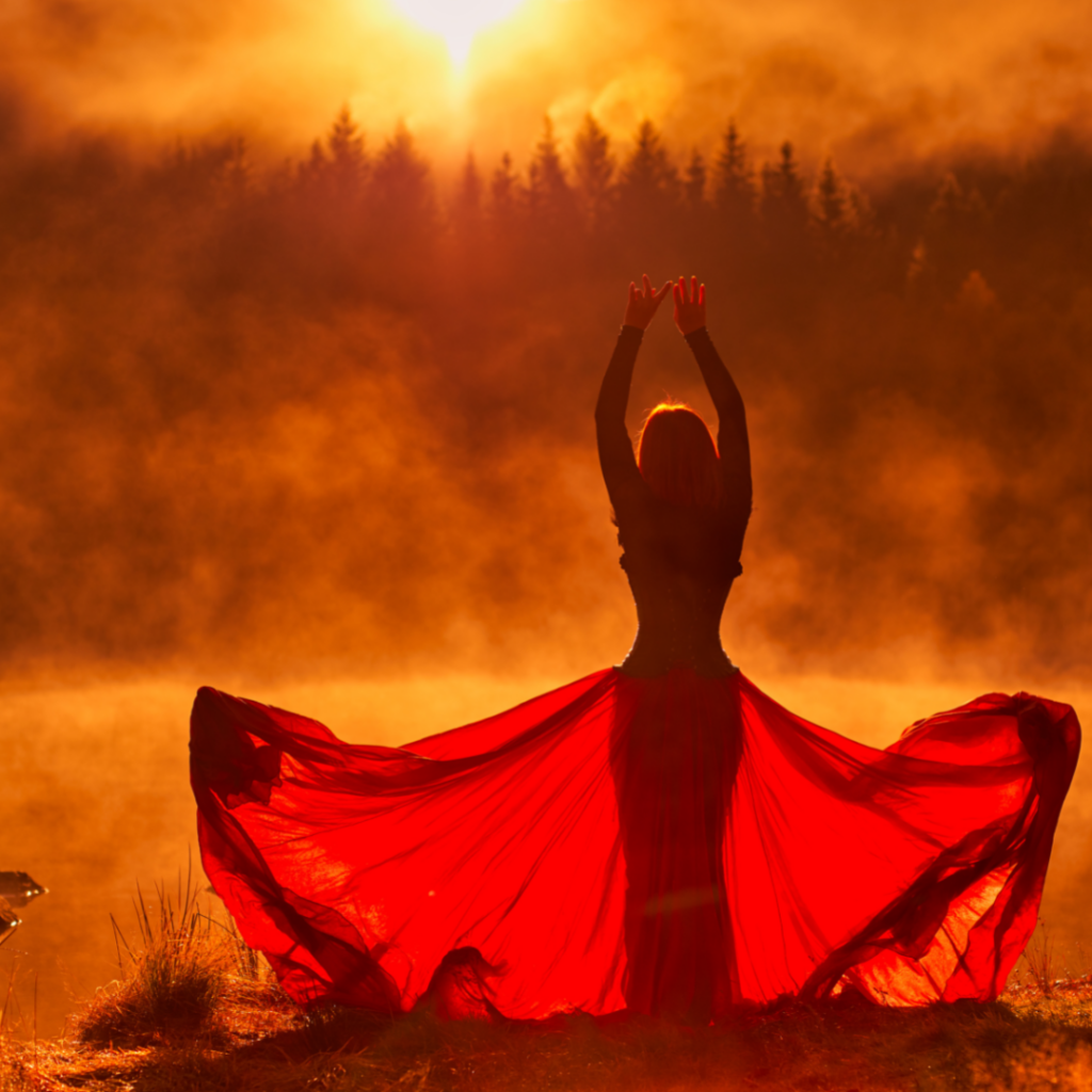 woman in flowing red skirt silhouetted against a forest sunset