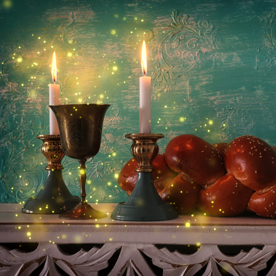 Glowing candles, ornate cup, and braided bread on a decorative table with a teal textured backdrop.