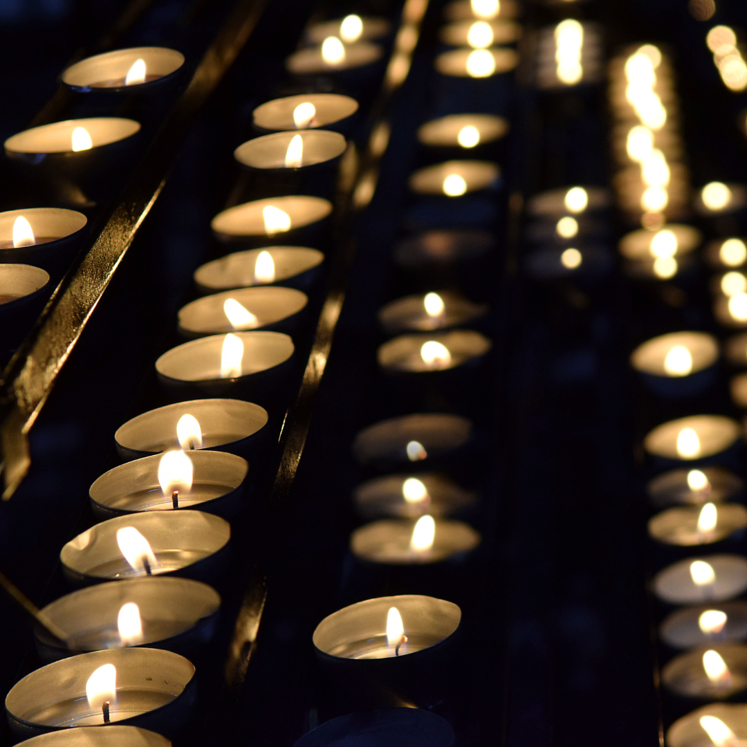 Rows of lit tea candles creating a warm, glowing ambiance in a dimly lit setting.