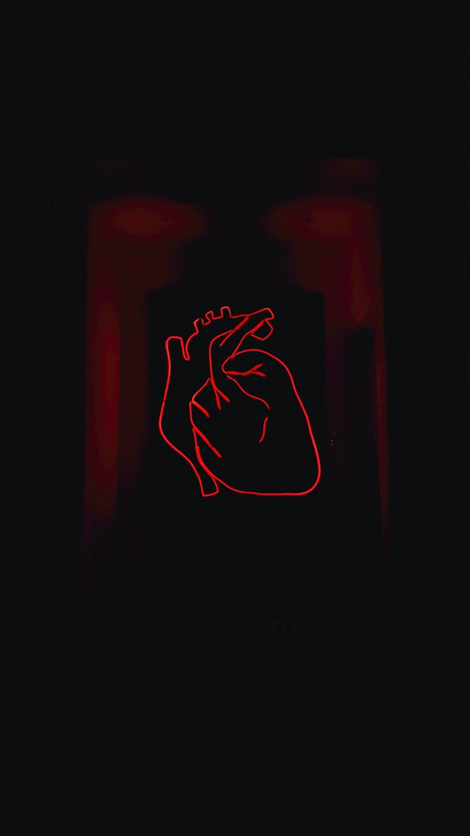 Red neon line art of a human heart on a dark background.