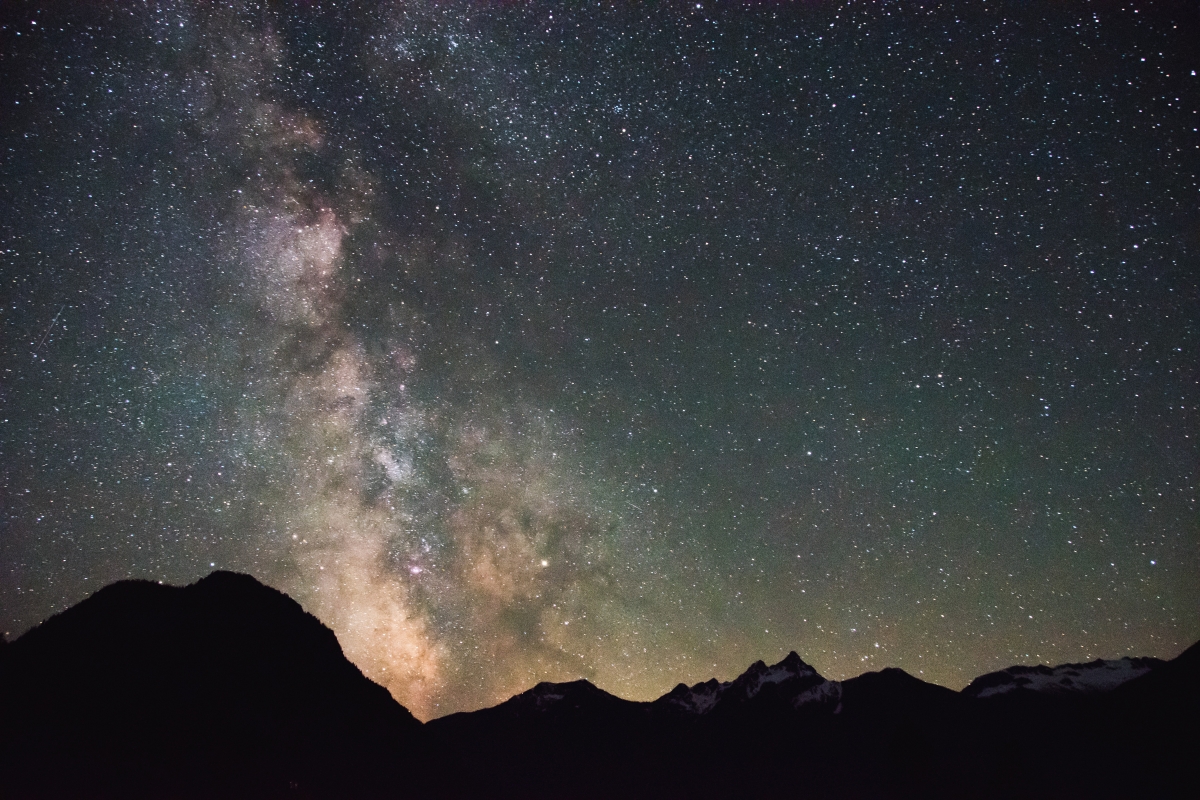 Starry night sky with the Milky Way over silhouetted mountain peaks.