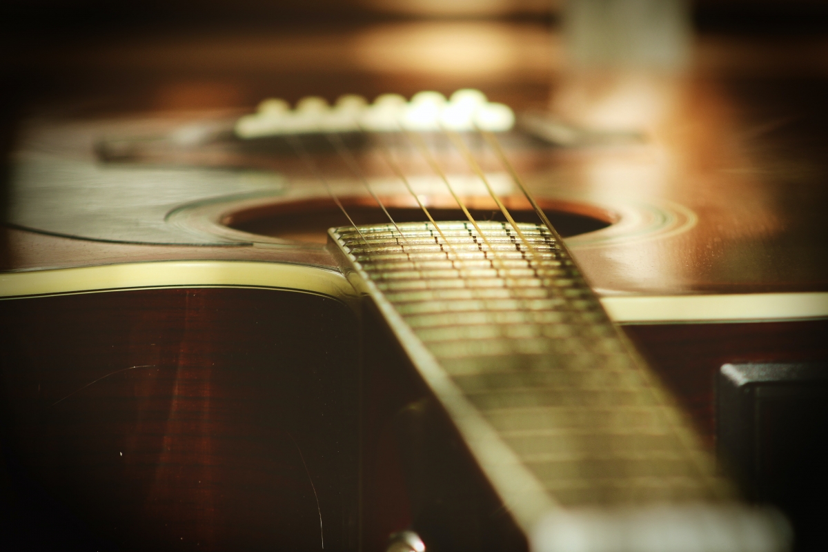 Close-up of an acoustic guitar focusing on the strings and body, with warm, soft lighting.