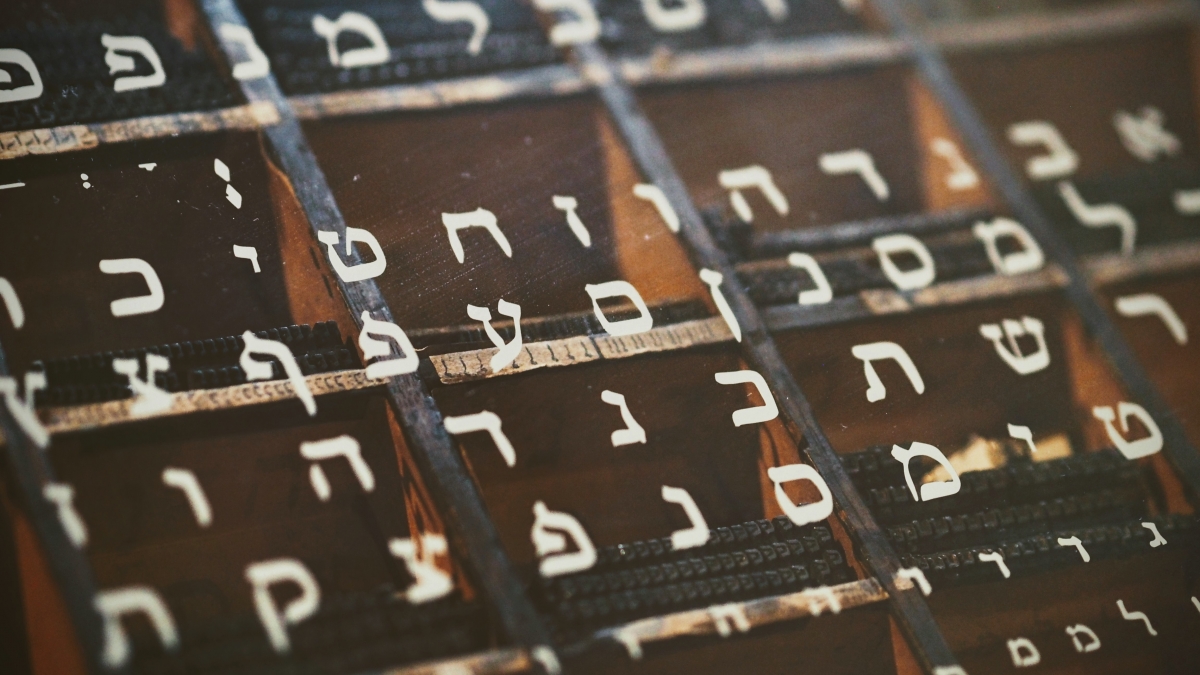 Close-up of Hebrew letters on pieces of metal type in a vintage print tray.