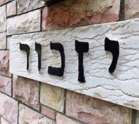 sign in hebrew that reads "yizkor" memorial - black letters on white stone