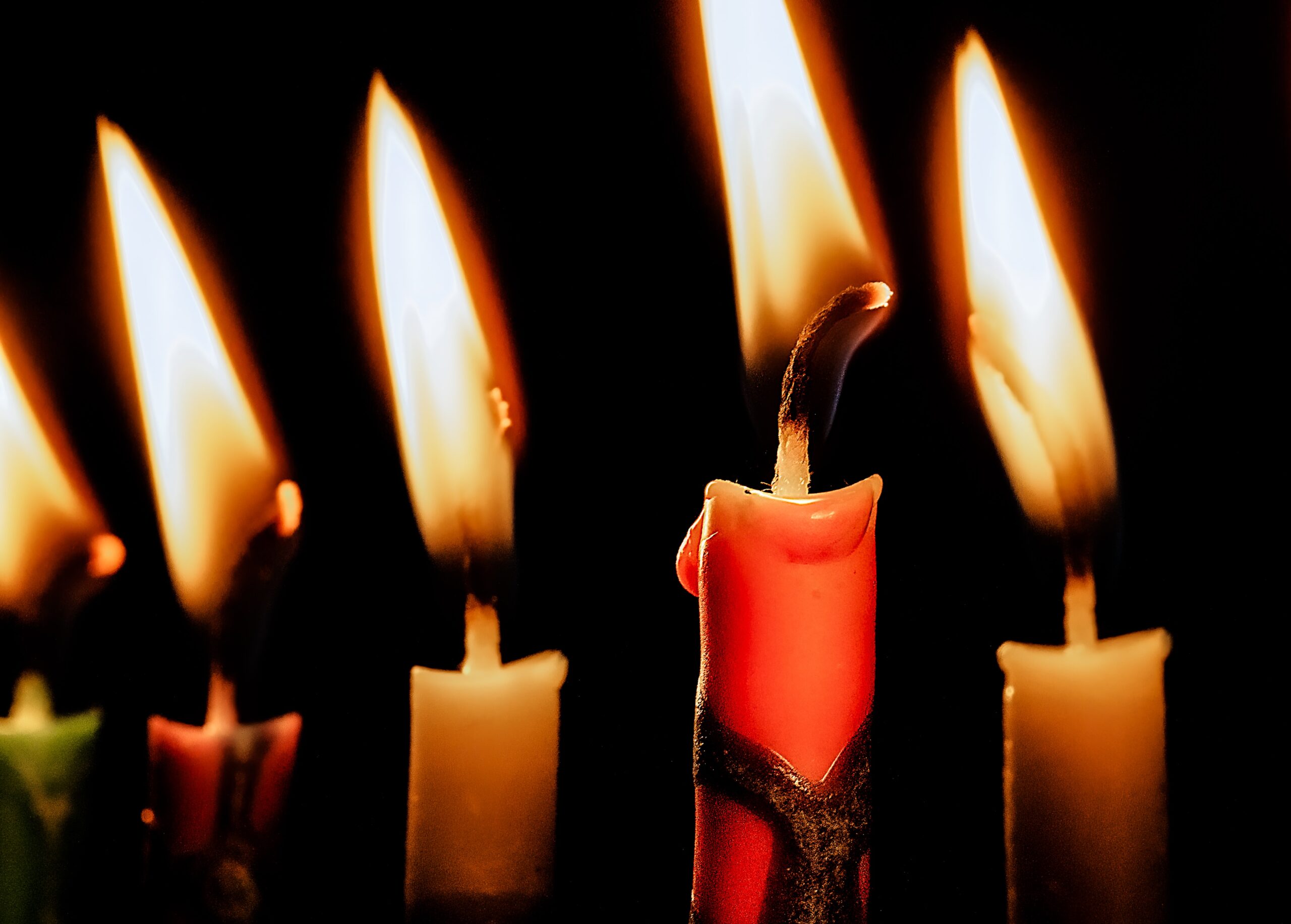 close up of five hanukkah candles burning in the dark