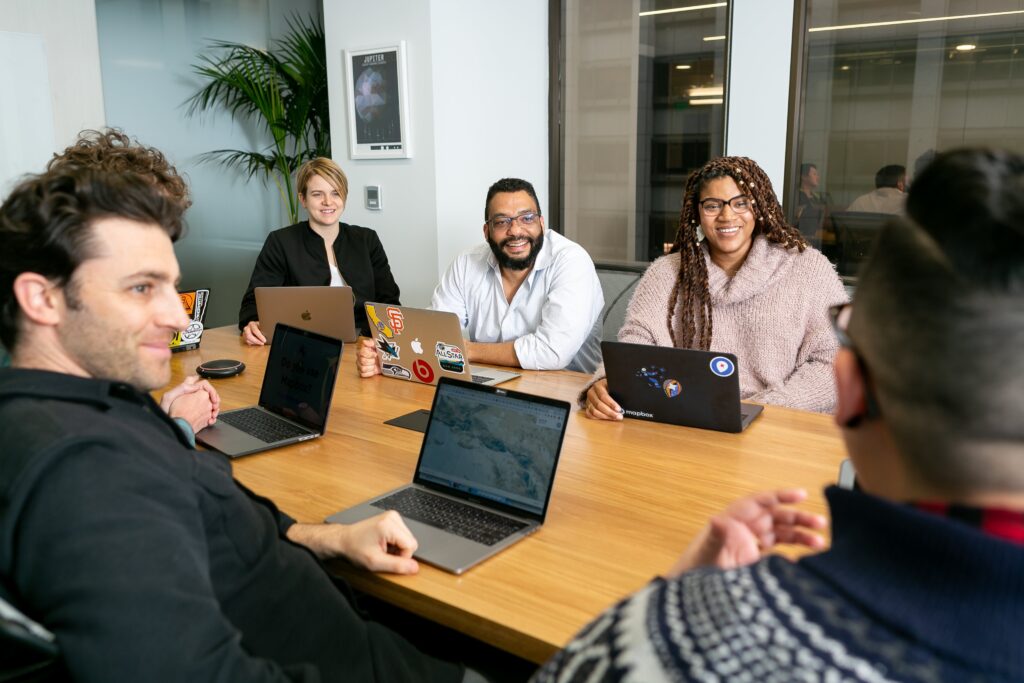 racially diverse group of people smiling around an office table
