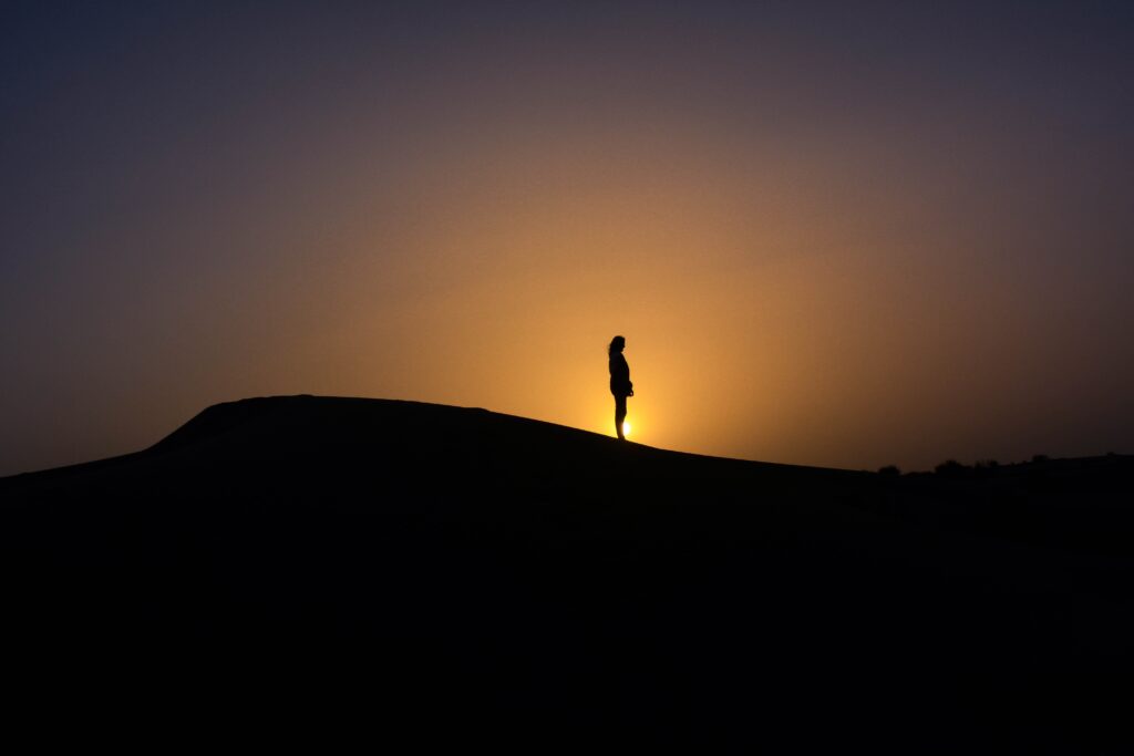 woman in profile standing on sand dune in the desert