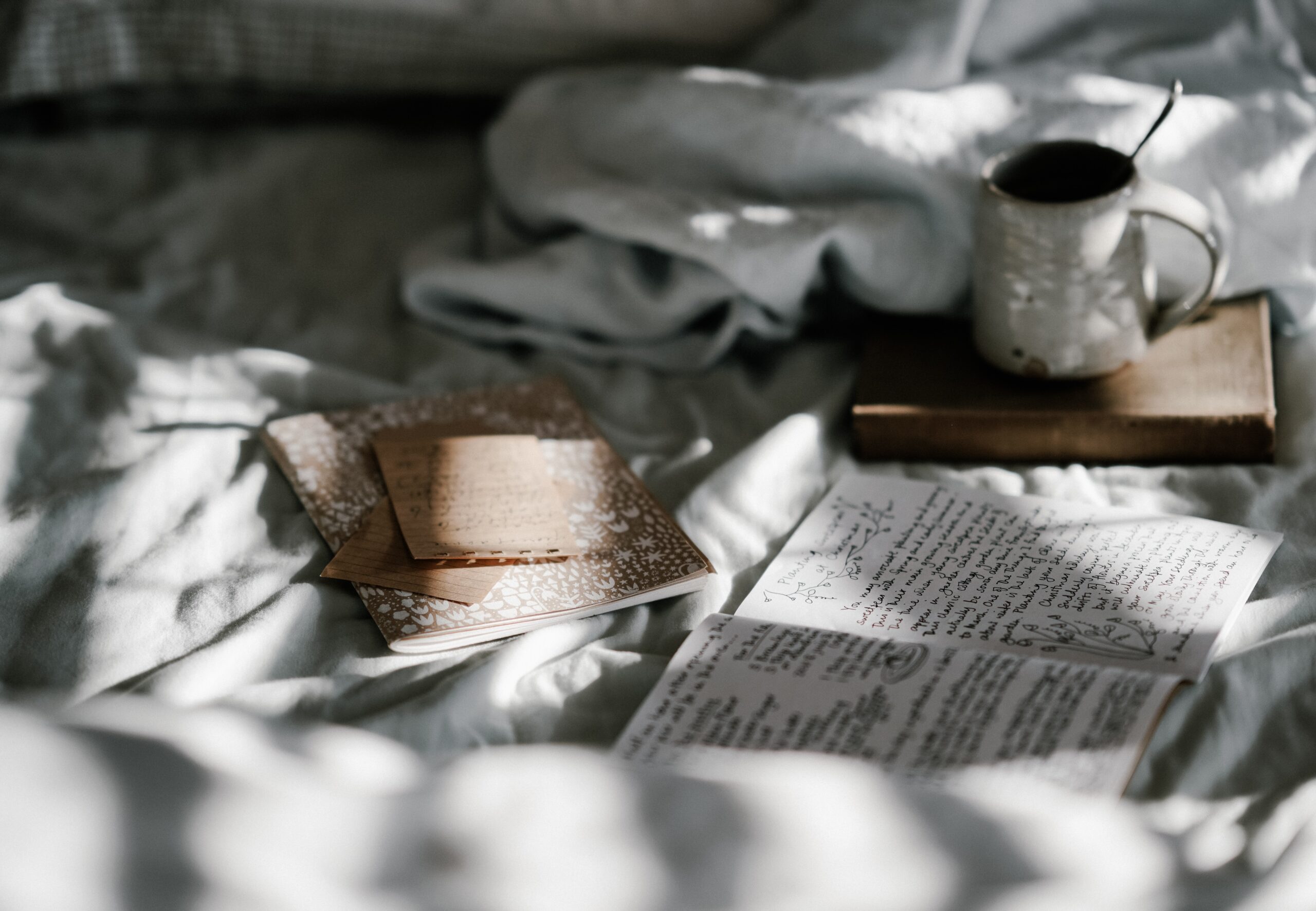 journals and tea on a sun dappled bedspread