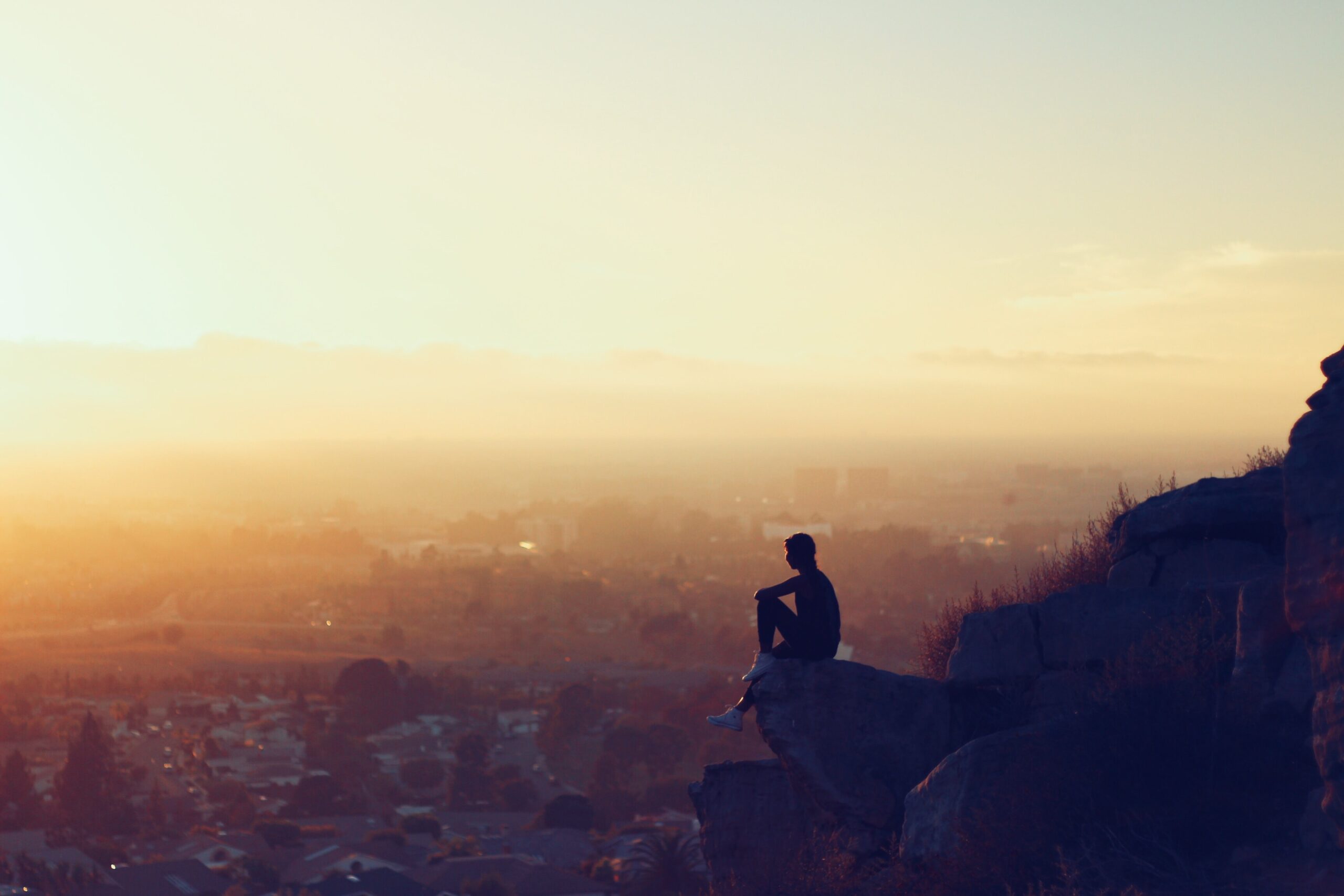 person overlooking the city from a mountain ledge