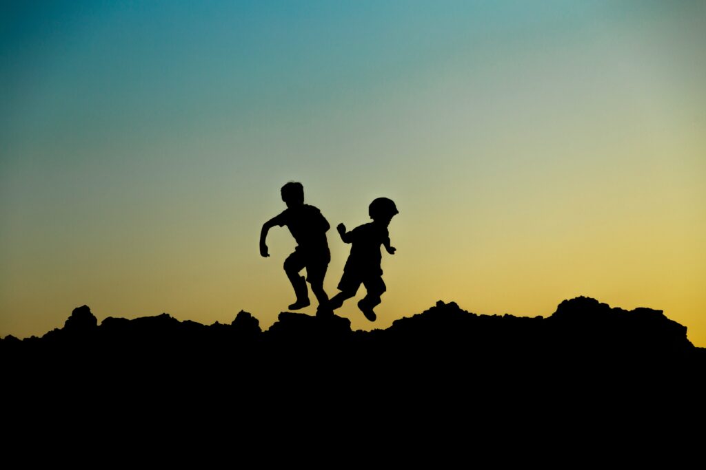 children in silhouette playing on the rocks