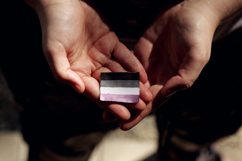 two hands holding small paper asexual flag