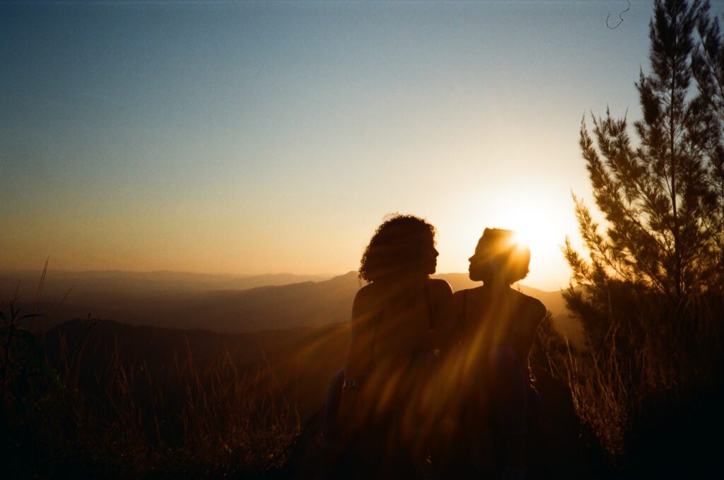 two people in silhouette on a mountaintop at sunset